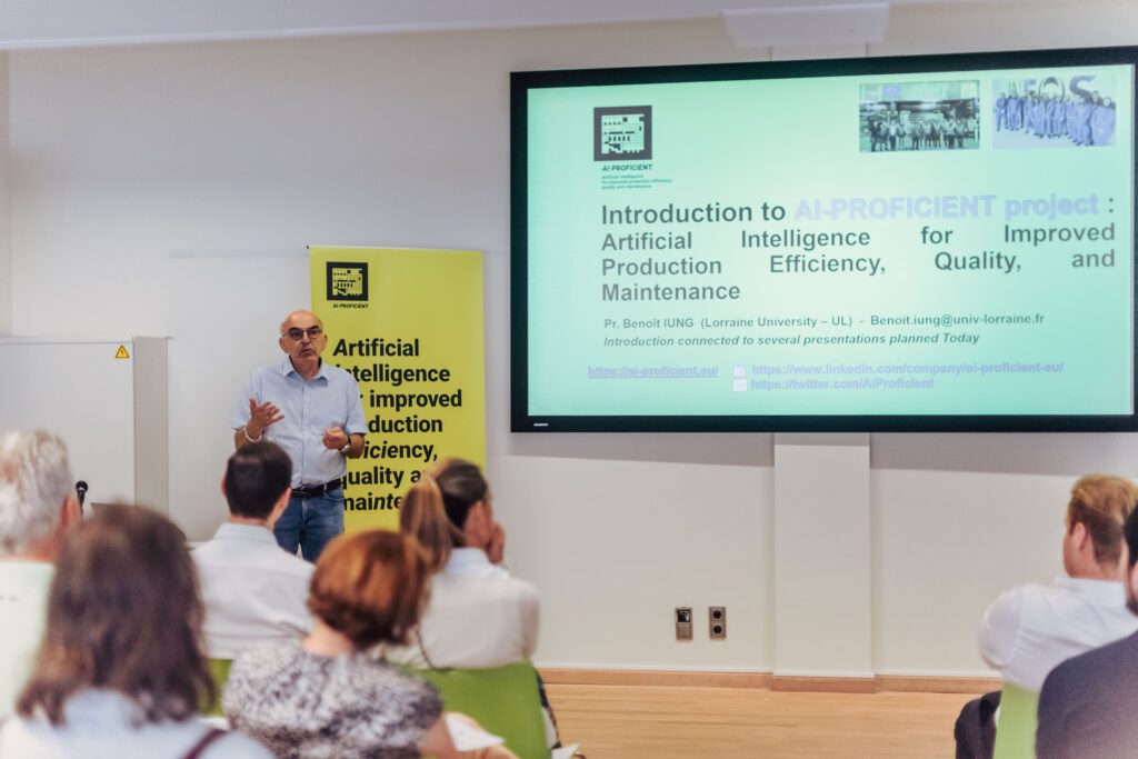 Professor Benoit Iung leading a presentation with a powerpoint screen behind him and seating audience of business men and women.