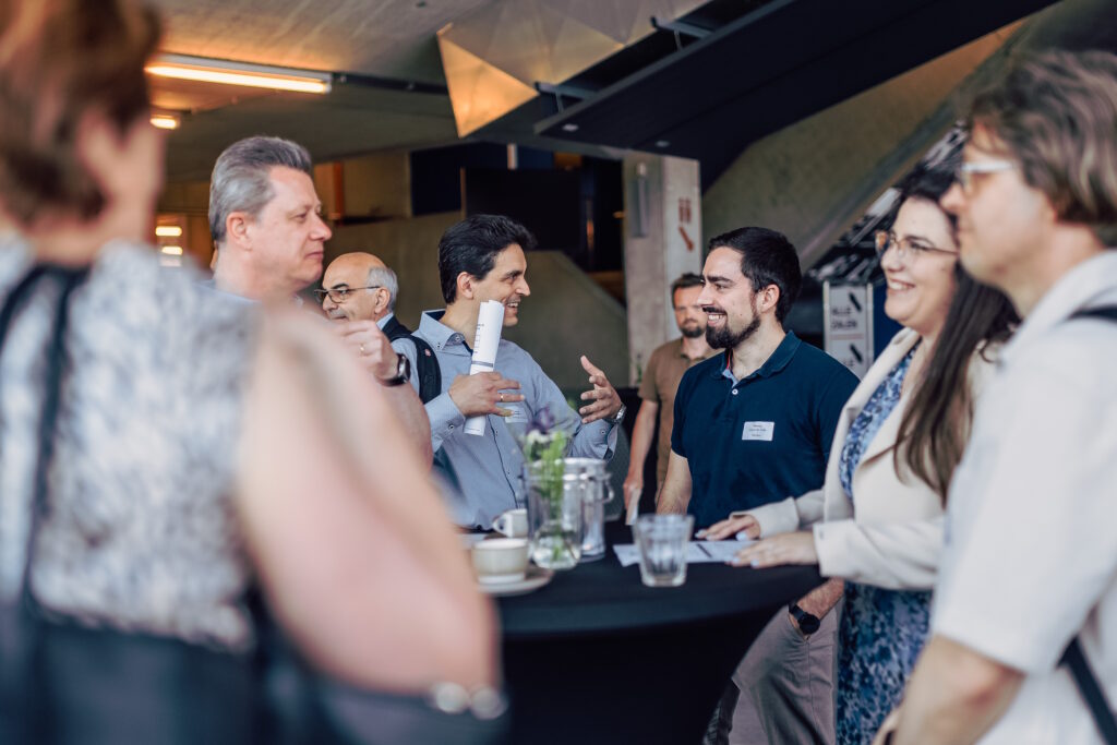 Business men and women networking around a round cocktail table.